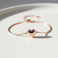 Pulseira Coração - semijoia rosé gold com pingente coração sobre mesa branca