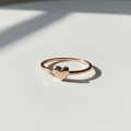 Anel Coração Delicado - semijoia rosé gold com detalhe de coração sobre mesa branca