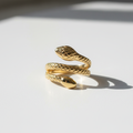 Anel Serpente Moderna - semijoia dourada com design de serpente sobre mesa branca