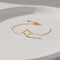 Pulseira Trevo - semijoia dourada com detalhe de trevo sobre mesa branca