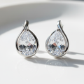 Brinco Gota Cristal - semijoia prateada com pedra cristal em formato de gota sobre mesa branca