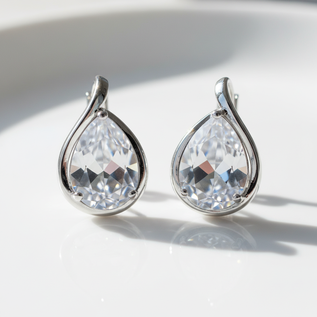 Brinco Gota Cristal - semijoia prateada com pedra cristal em formato de gota sobre mesa branca